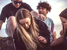 Vier Jugendliche sitzen auf einem Stein.