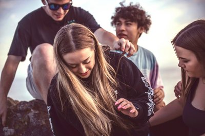 Vier Jugendliche sitzen auf einem Stein.