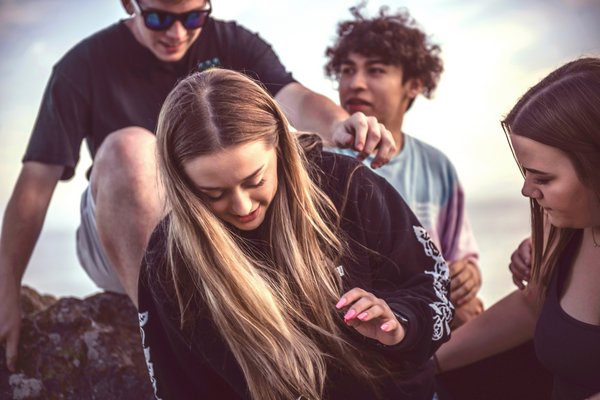 Vier Jugendliche sitzen auf einem Stein.