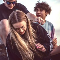 Vier Jugendliche sitzen auf einem Stein.